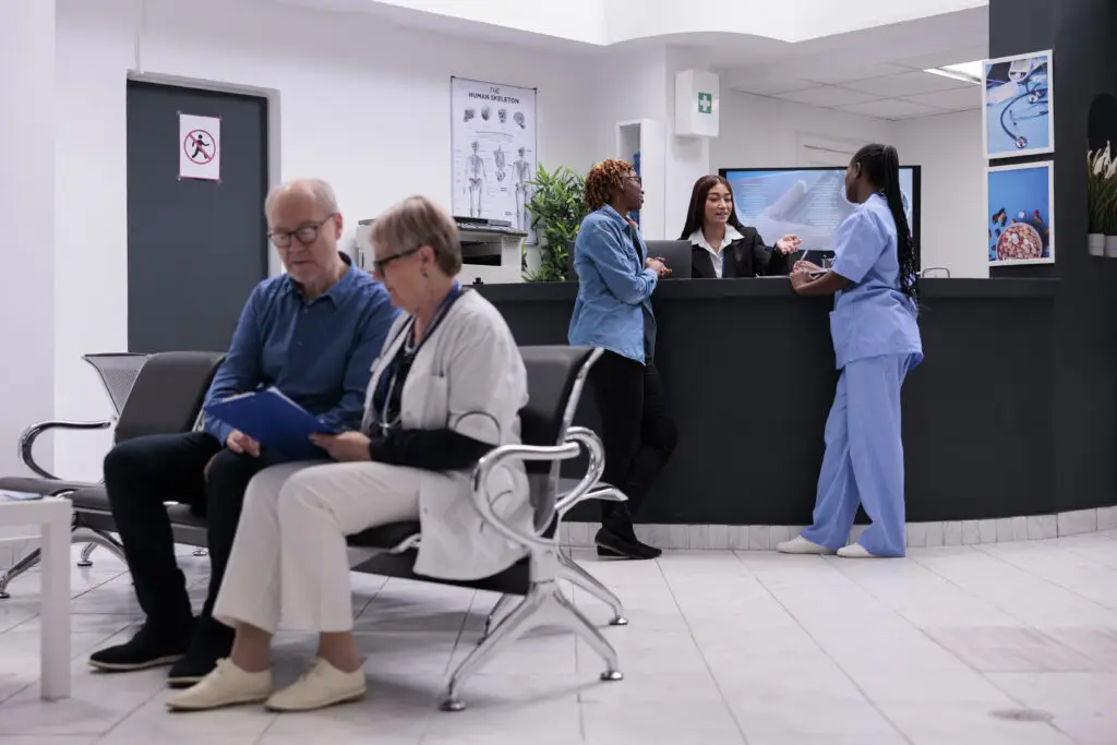5 dicas para otimizar sua clÃnica de saúde 1 patient nurse sitting reception desk talking female receptionist about disease diagnosis healthcare support diverse people working health center registration counter 1 1024x683 2